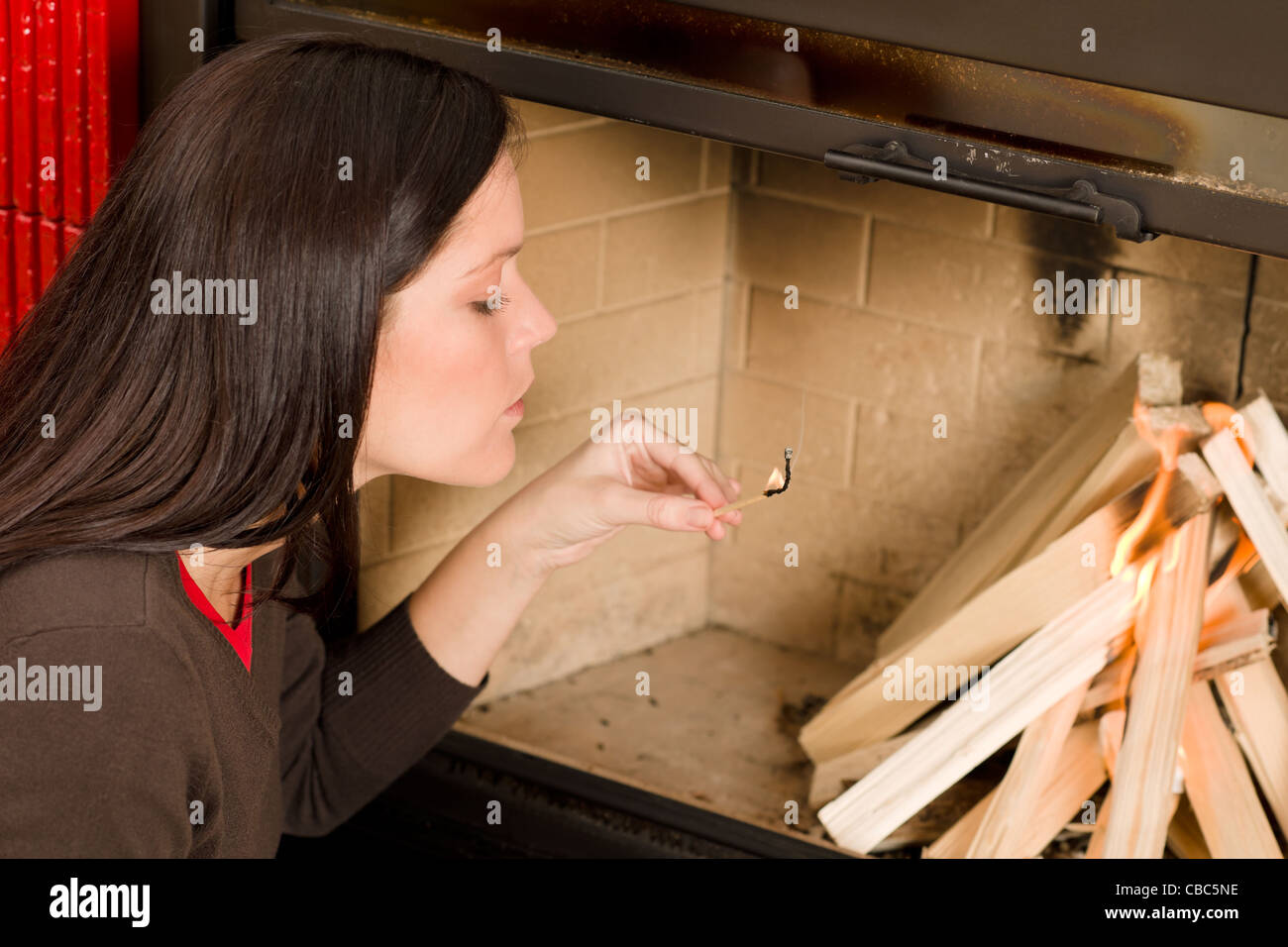 Young Woman Lighting Up Wood Logs In Fireplace Home Living Stock