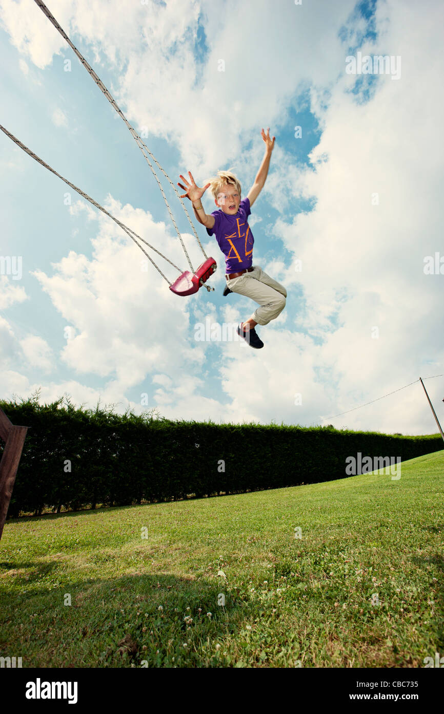 Boy jumping off swing in backyard Stock Photo Alamy