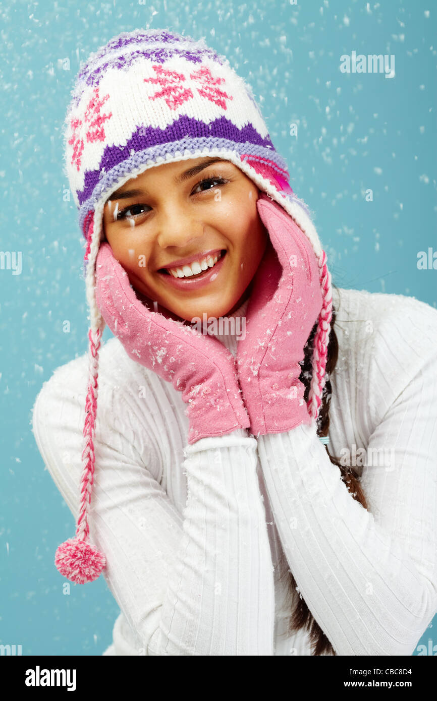 Portrait of pretty woman in pink gloves and knitted winter cap looking at camera with smile Stock Photo