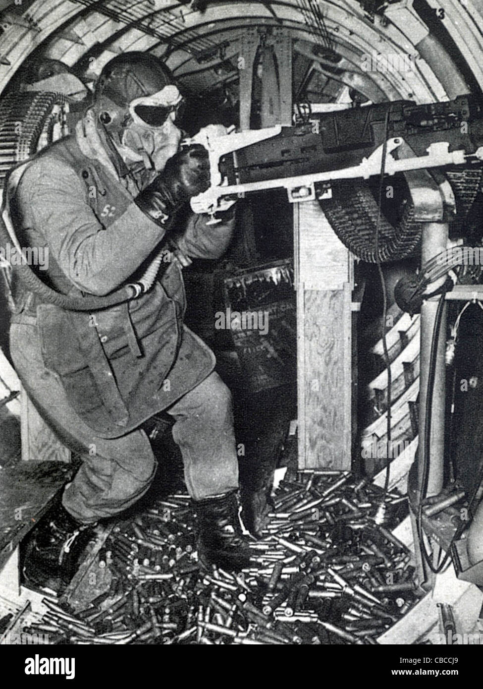 A WW11 USAAF B17 Flying Fortress wait gunner stands amid a heap of empty machine gun cases. Stock Photo