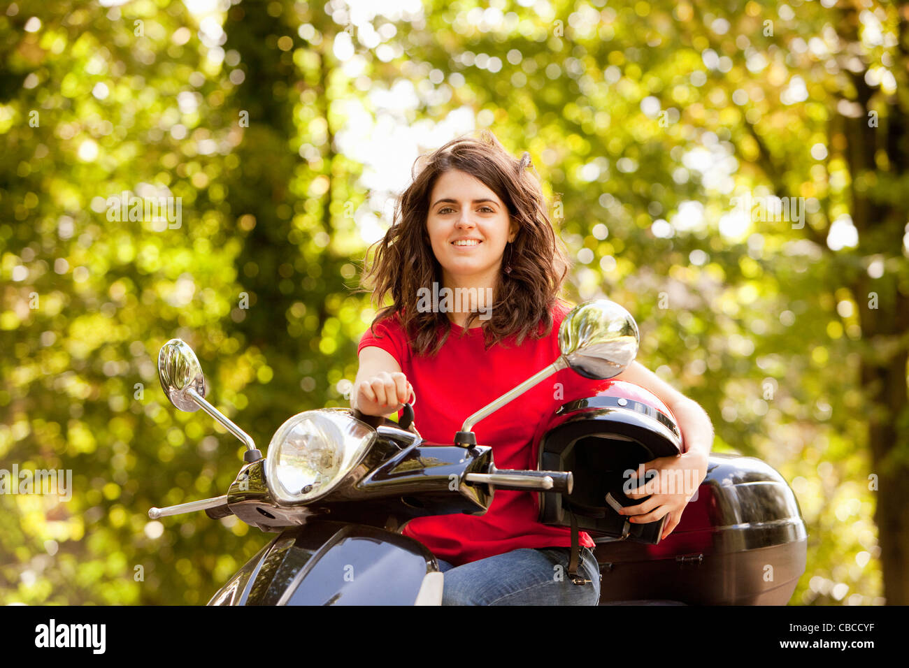 Woman sitting on scooter in park Stock Photo