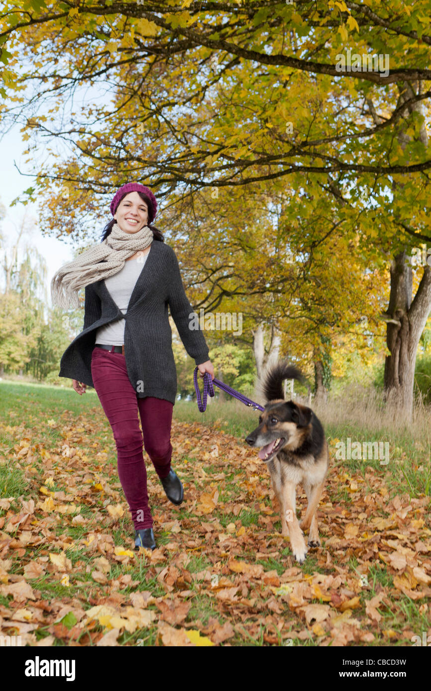 Smiling woman walking dog in park Stock Photo