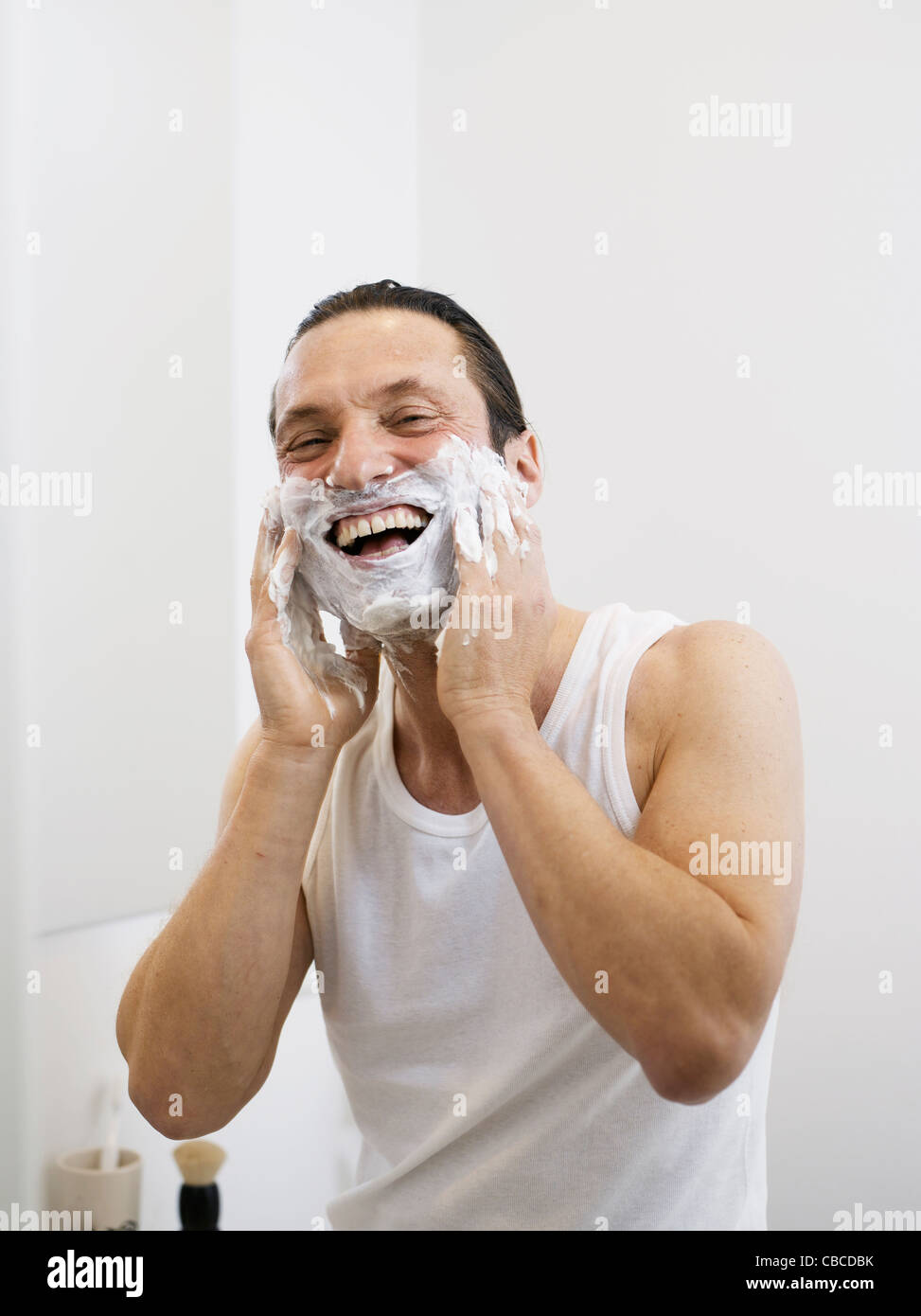 Smiling man lathering his beard Stock Photo