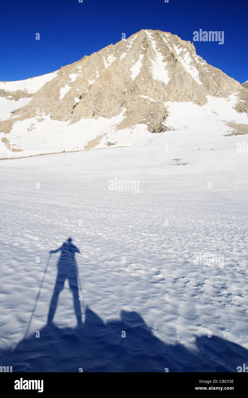 hiking man's shadow on snow and Mount Merriam in the Sierra Nevada mountains of California Stock Photo