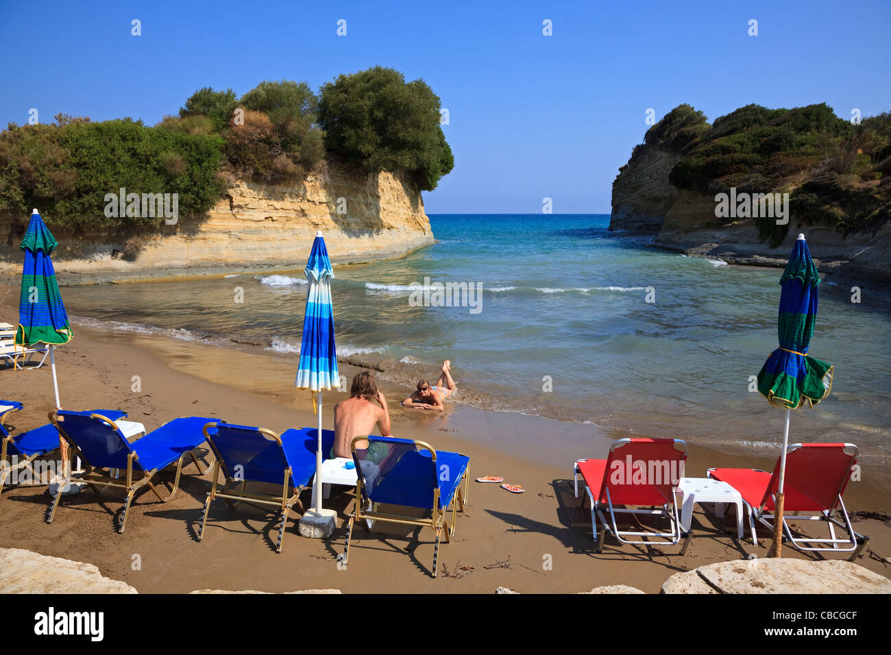 Secluded beach at Peroulades, near Sidari, Corfu, Greece with two tourists photographing each other Stock Photo