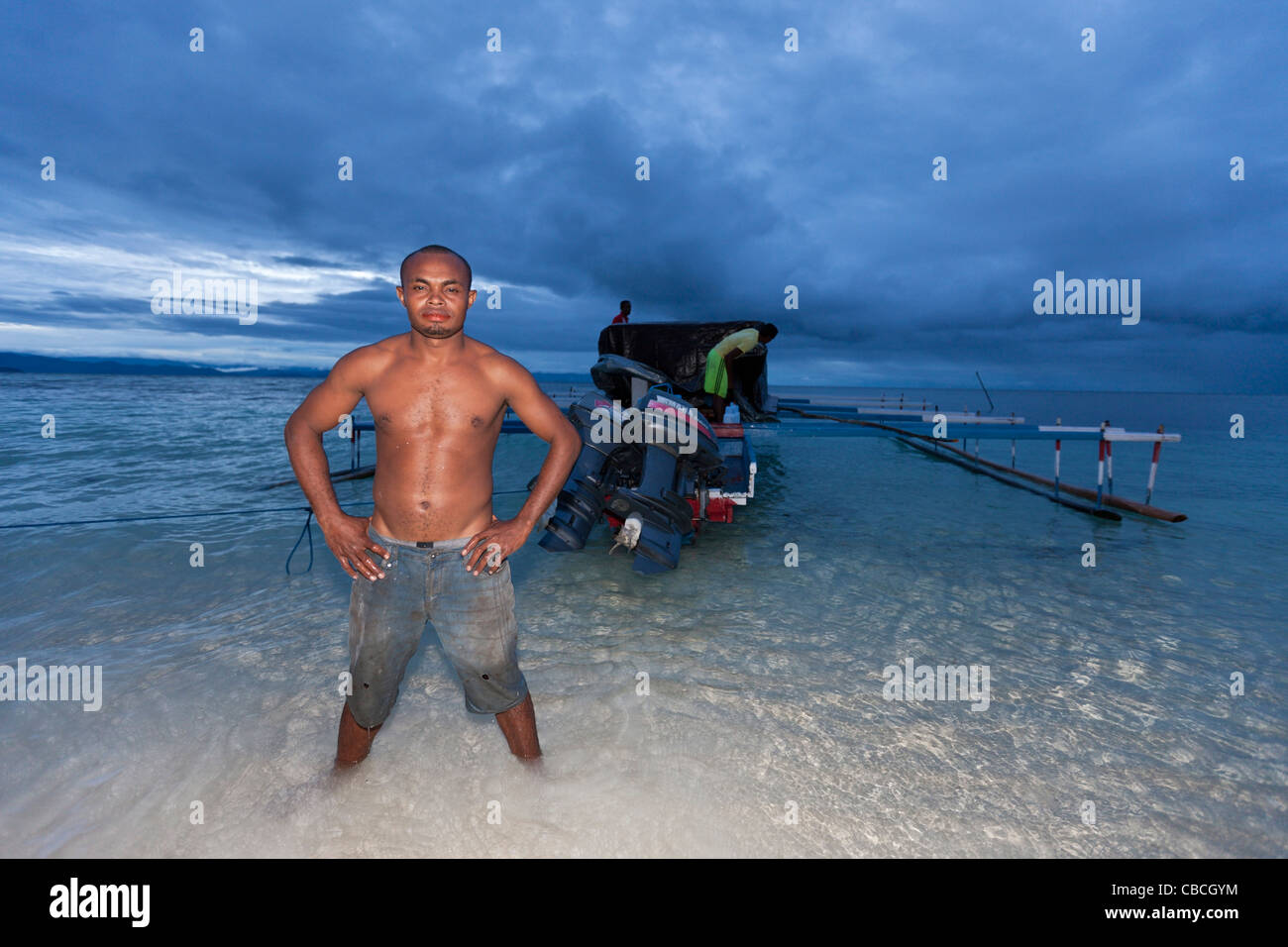 Boatman and his Outrigger Boat, Cenderawasih Bay, West Papua, Indonesia Stock Photo