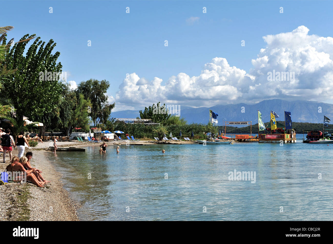 People enjoying the narrow strip of shingle beach at Nidri on the Ionian Island of Lefkas, Greece. Stock Photo