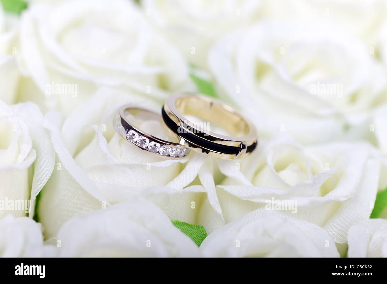 Two wedding rings concept on white roses bouquet. Stock Photo