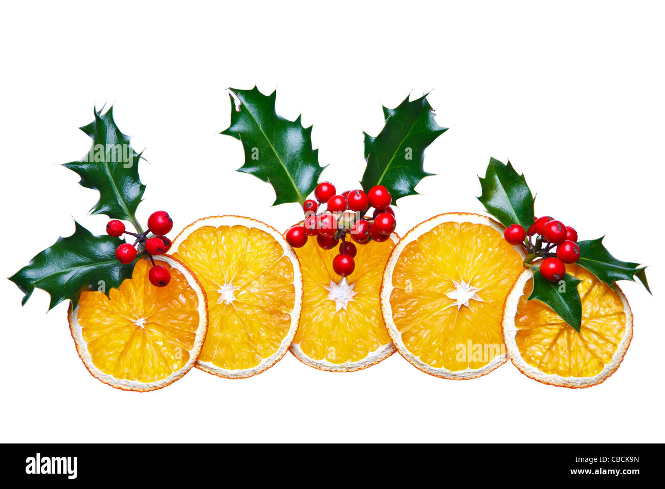 Photo of dried orange slices and holly with red berries arranged into a decorative Christmas