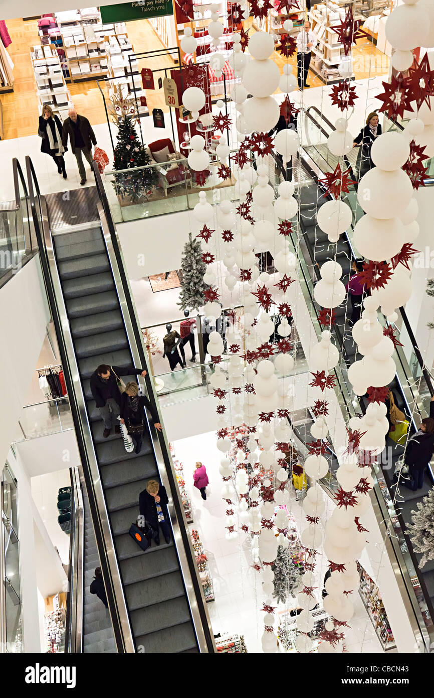Shopping in modern John Lewis department store with escalators and Christmas decorations, Cardiff, UK Stock Photo