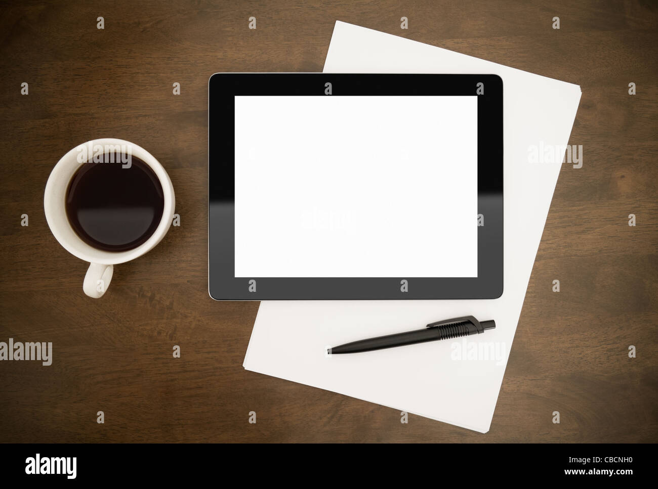 Contemporary digital tablet with blank screen lying on worktable with paper, pen and cup of coffee. Top directly above view. Stock Photo