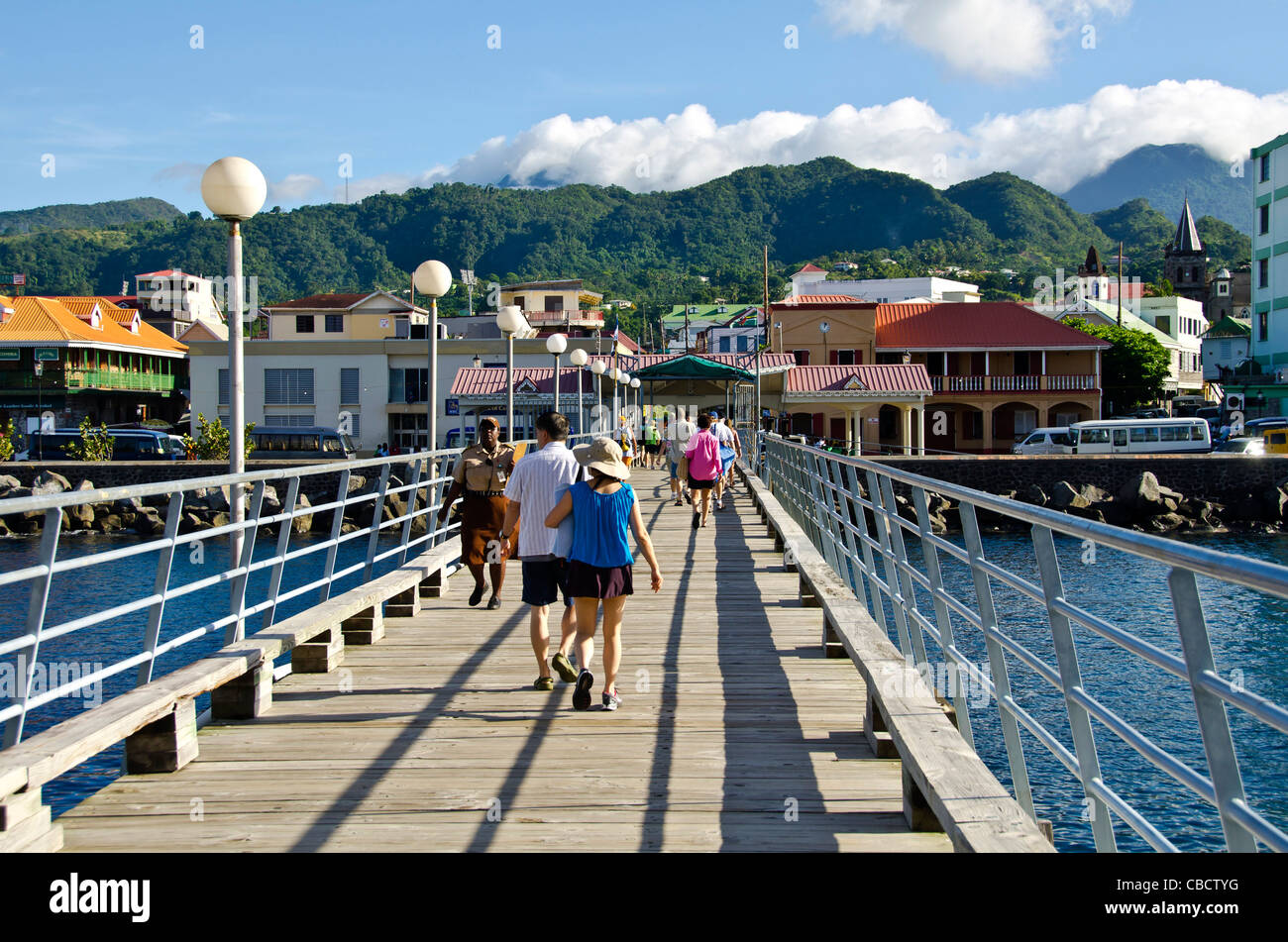 Cruise pier leading toward Roseau, Dominica, with cruise passengers walking on pier Stock Photo