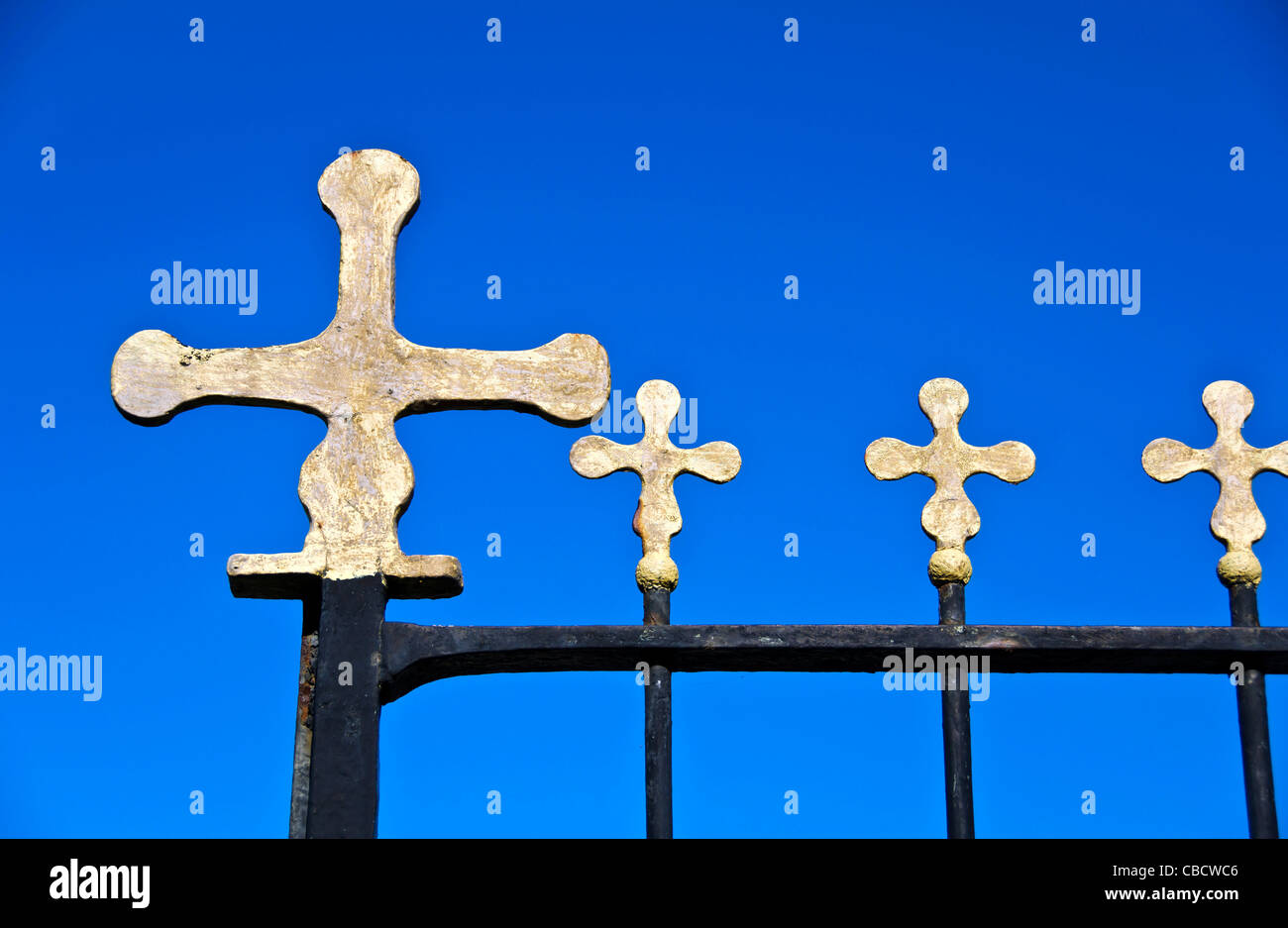 Closeup of horizontal row of gold Christian crosses on a black metal gate Stock Photo