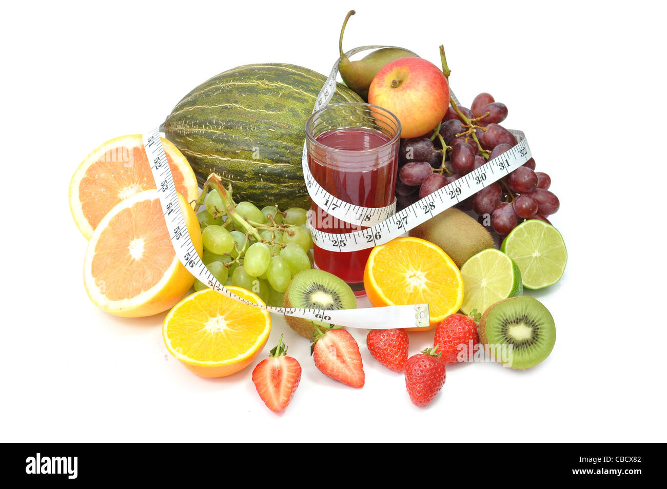 Fresh glass of juice surrounded by an assortment of fruit and a tape measure Stock Photo