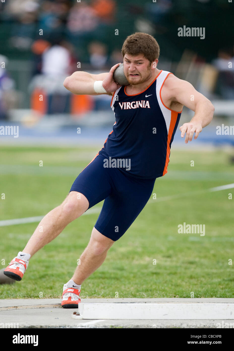 A male athlete throws a shot put during a track and field meet Stock