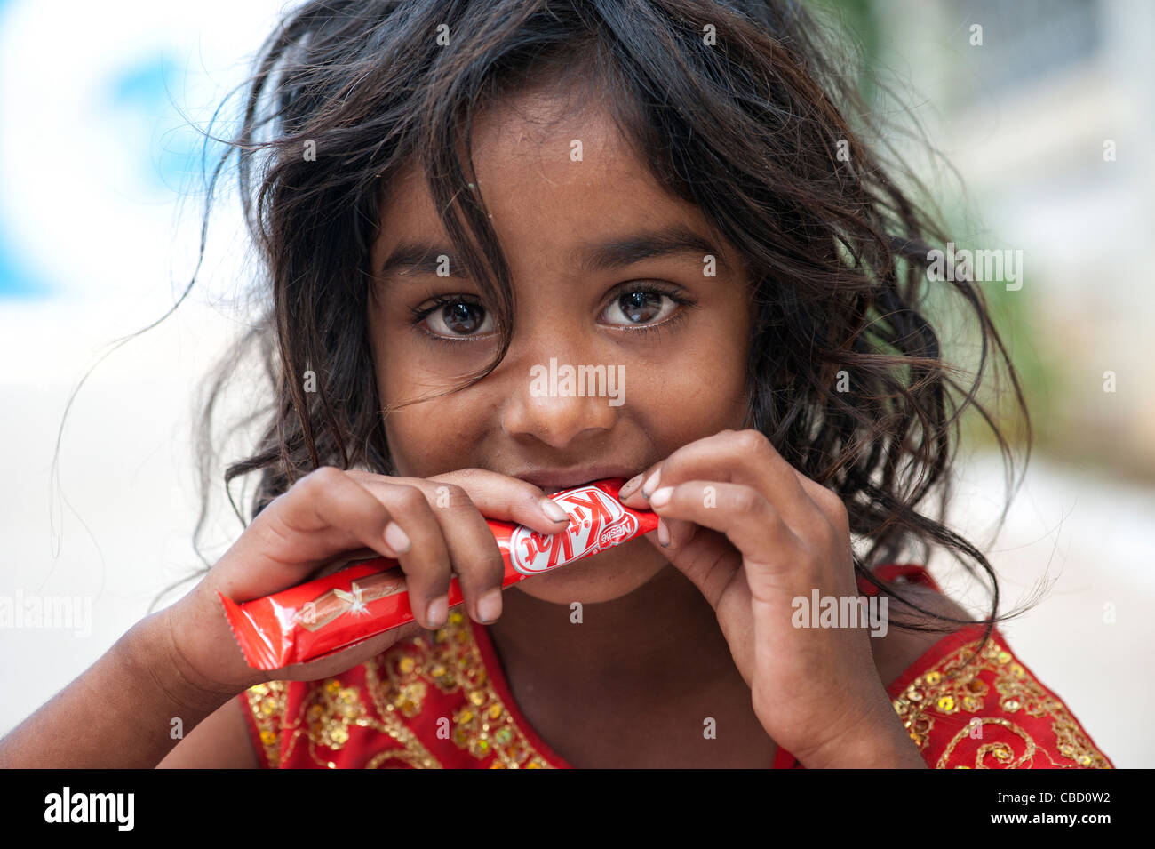 Young poor lower caste Indian street girl holding and opening a chocolate bar. Andhra Pradesh, India Stock Photo