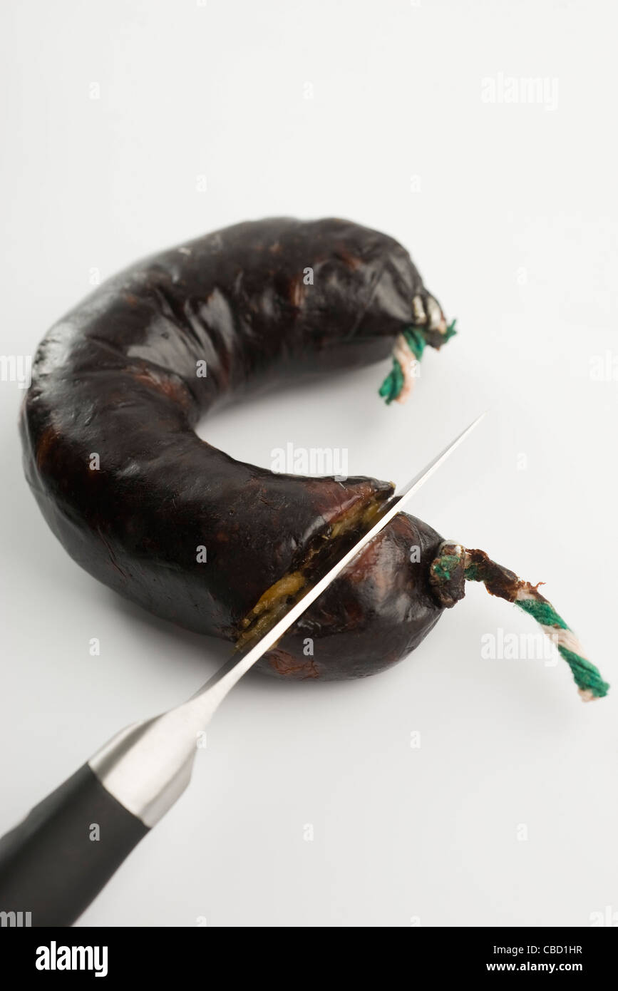 Cutting blood sausage with a knife Stock Photo