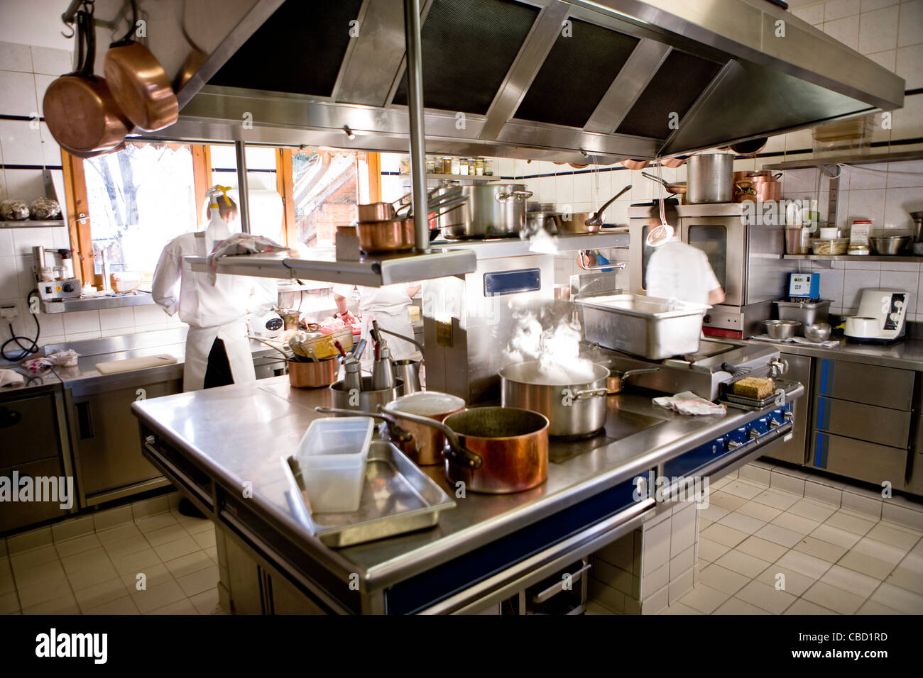 Chefs working in commercial kitchen, pot cooking on stove Stock Photo
