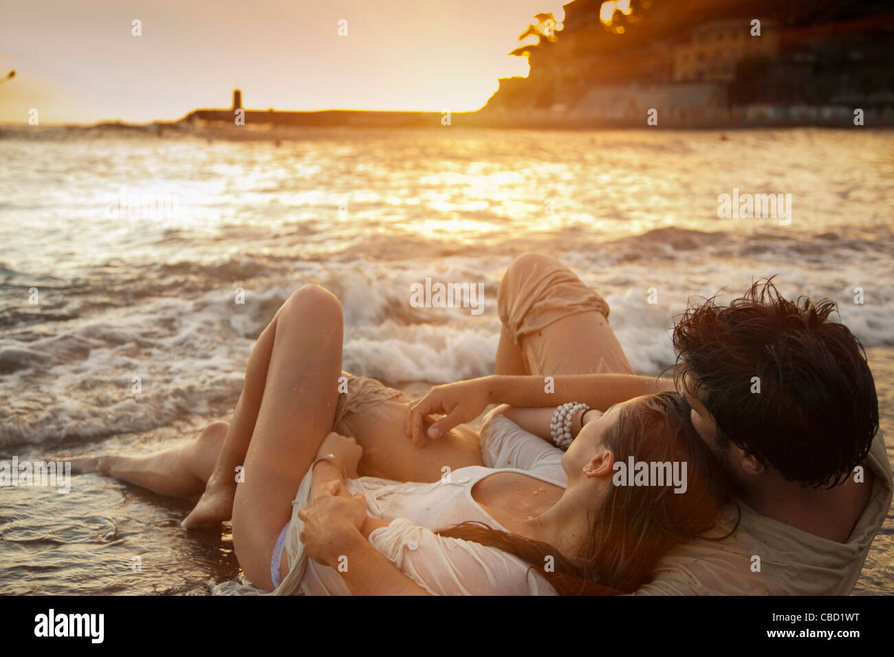 Couple laying on sand at beach Stock Photo