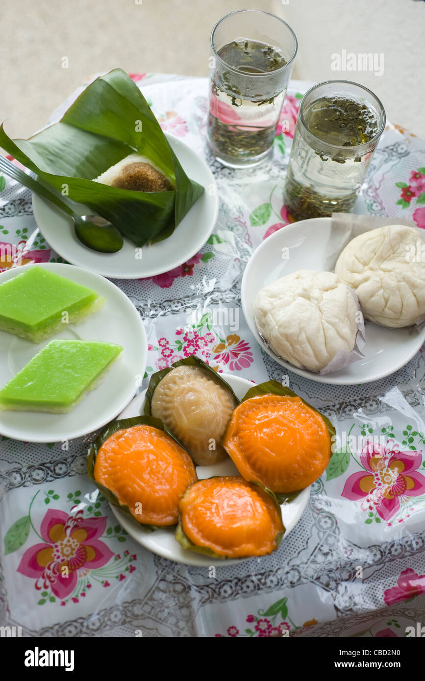 Assortment of Malaysian fare: kueh-mueh (rice cakes), steamed buns, pulut inti and tea Stock Photo