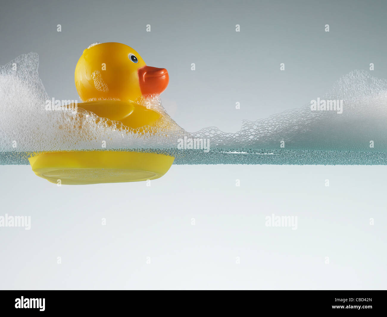 Rubber duck floating in soapy water Stock Photo