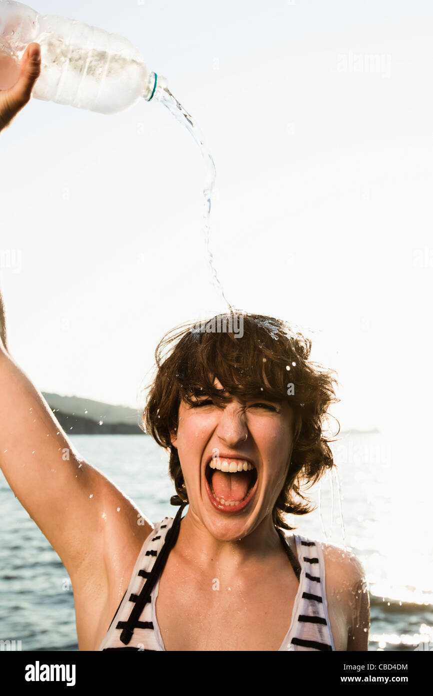 Woman pouring water on herself at beach Stock Photo - Alamy