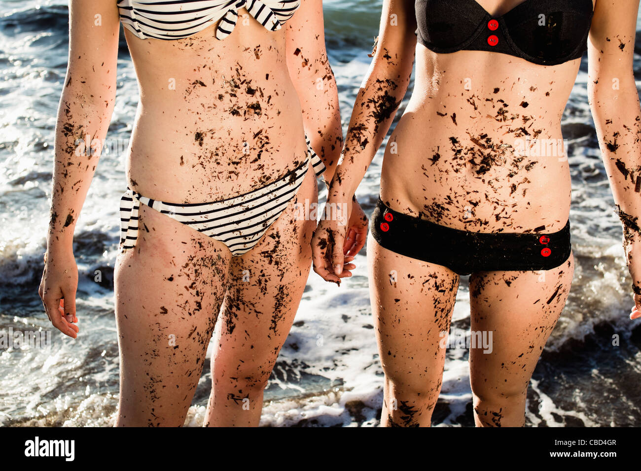 Women covered in sand on beach Stock Photo
