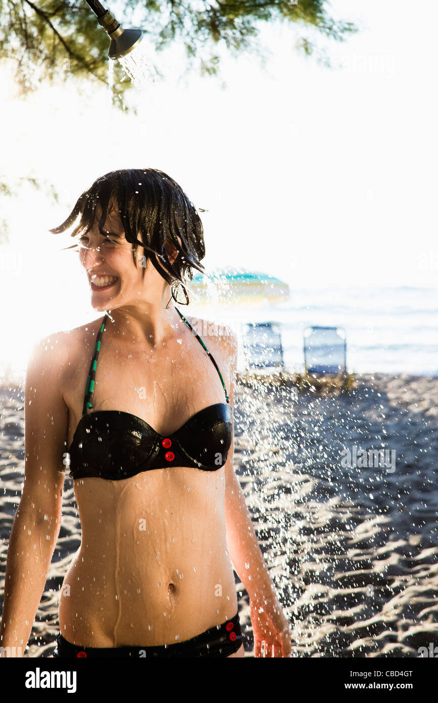 Woman standing in shower at beach Stock Photo
