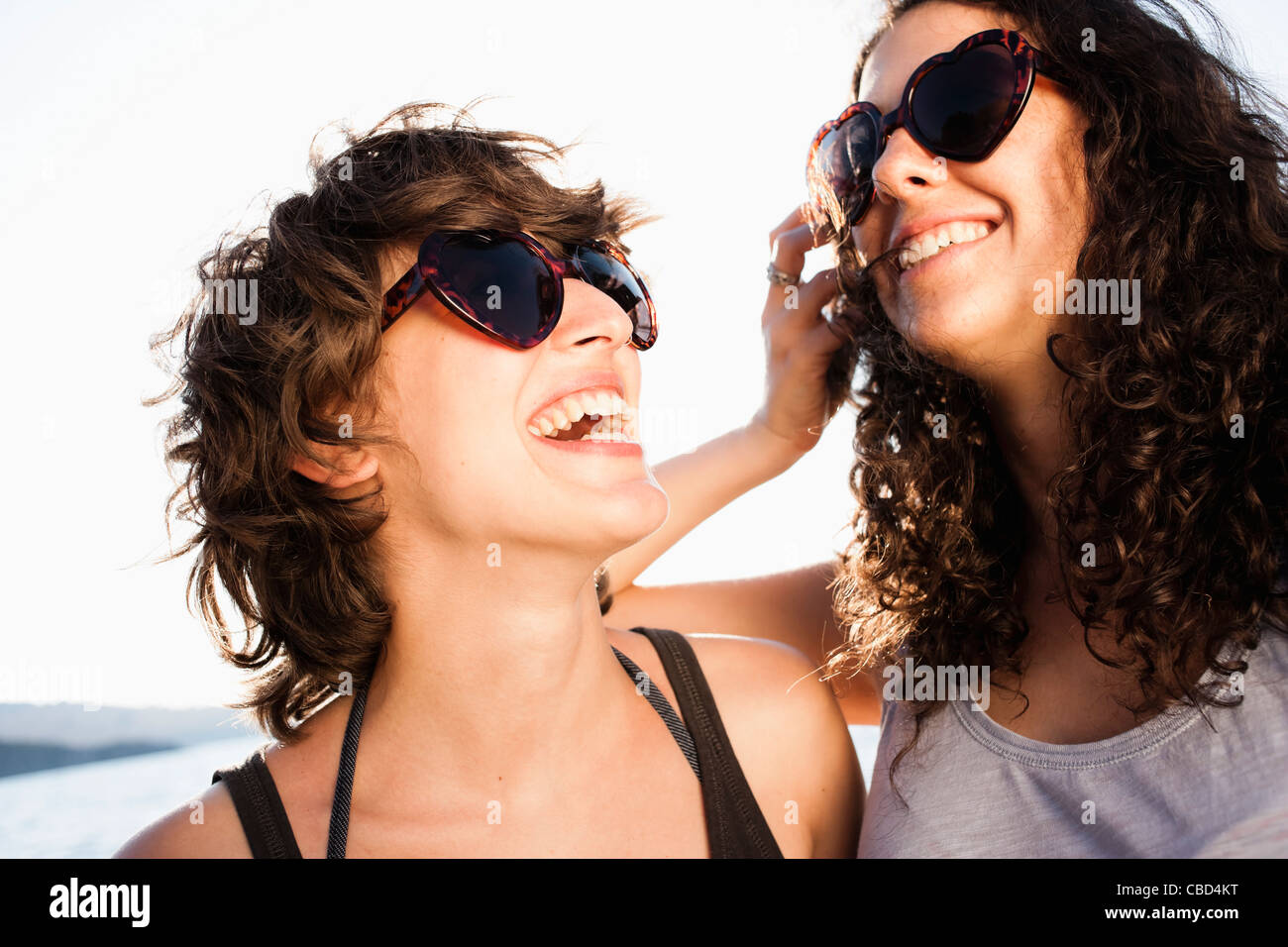 Laughing women in sunglasses on beach Stock Photo