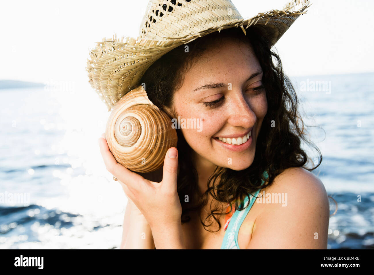 Woman listening to seashell on beach Stock Photo