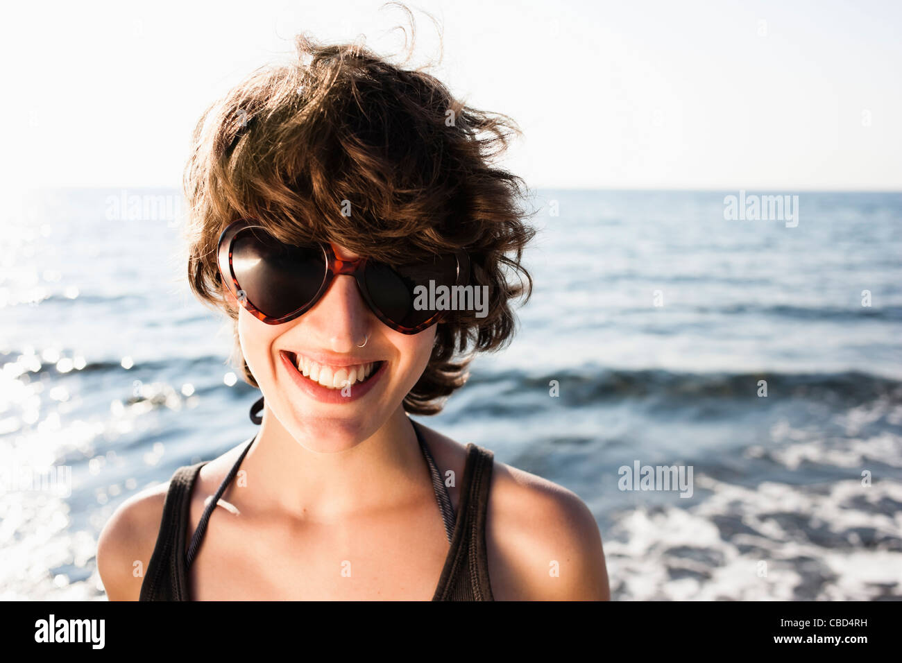 Smiling woman in sunglasses on beach Stock Photo