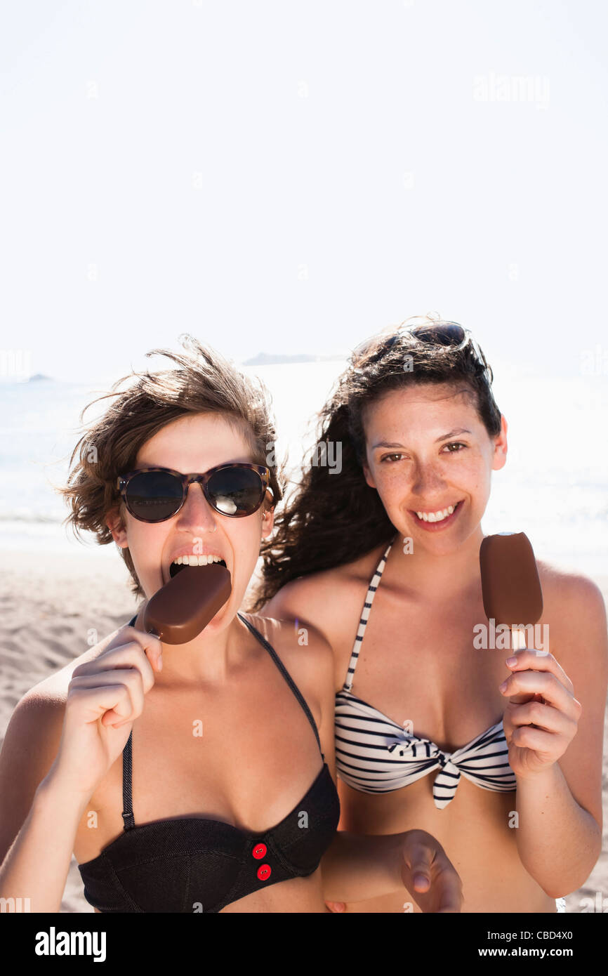 Women eating ice cream on beach Stock Photo