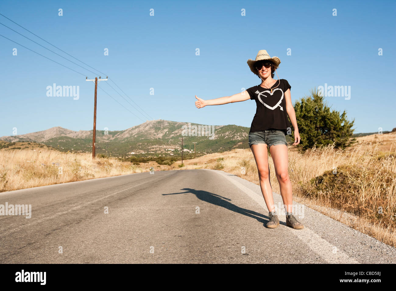 Woman hitch hiking on rural road Stock Photo