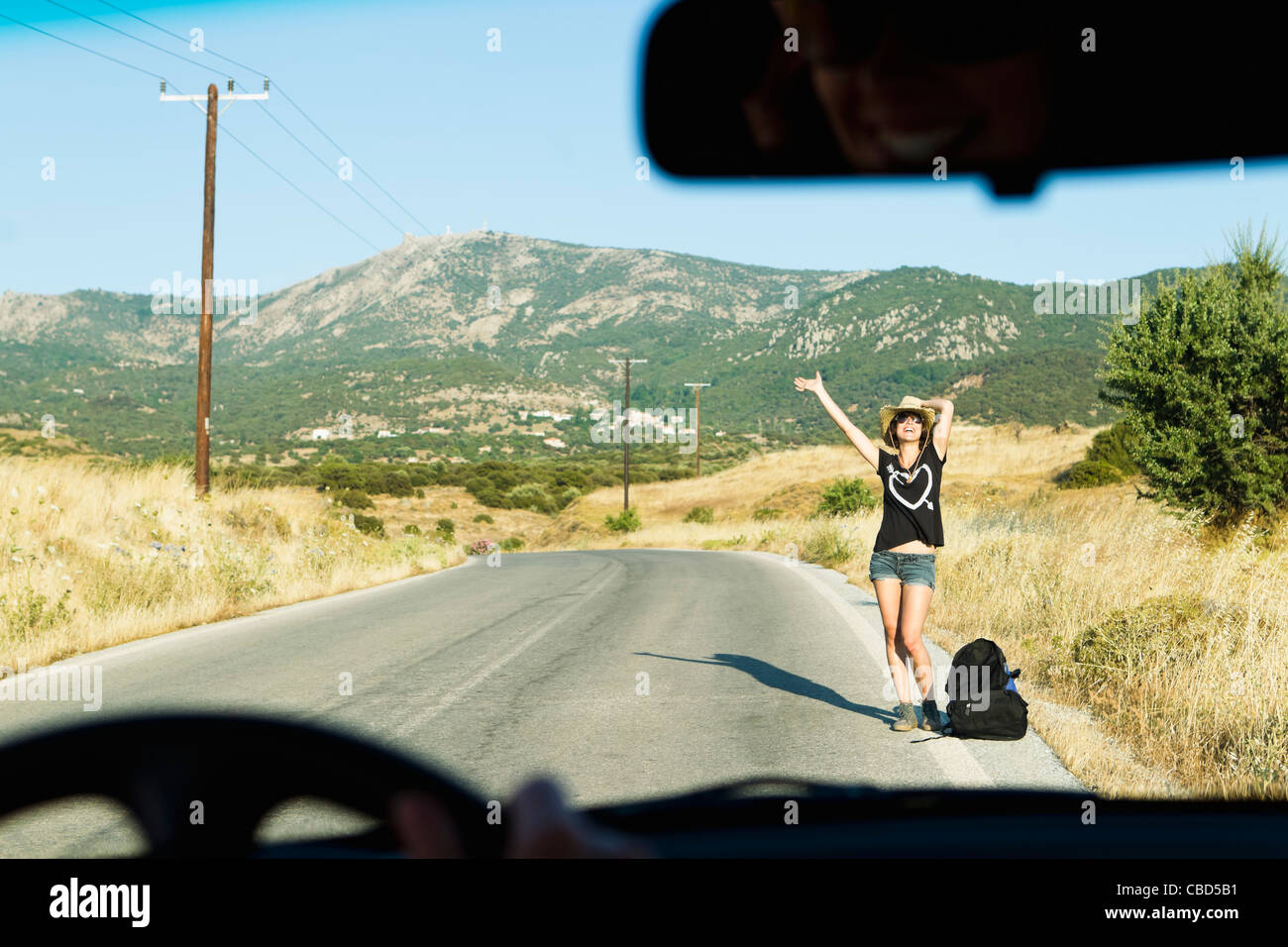 Woman hitch hiking on rural road Stock Photo - Alamy