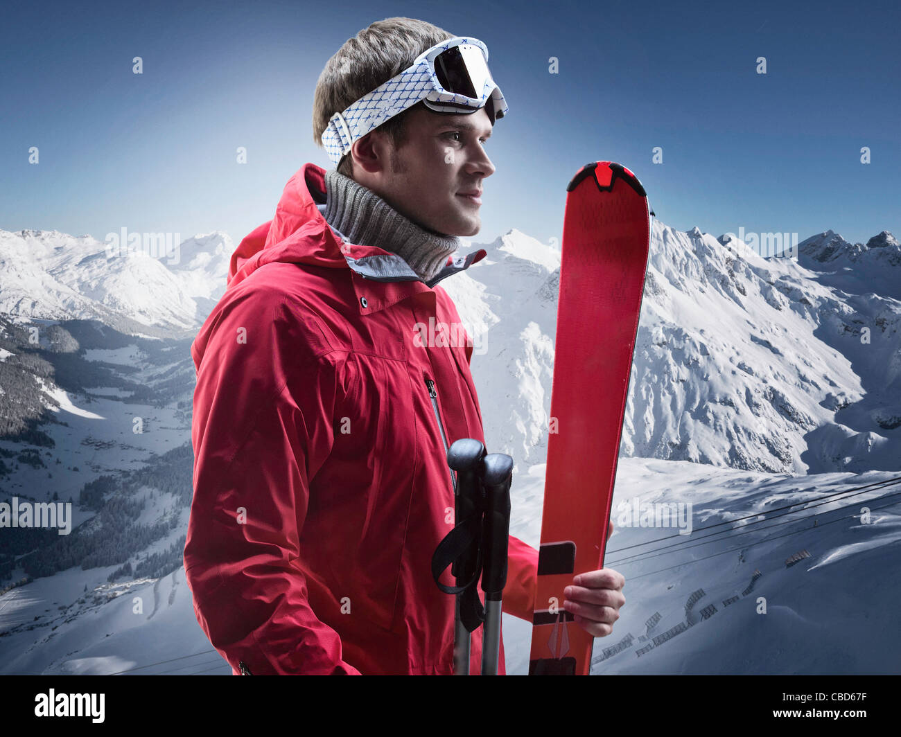 Man carrying skis on snowy mountain Stock Photo
