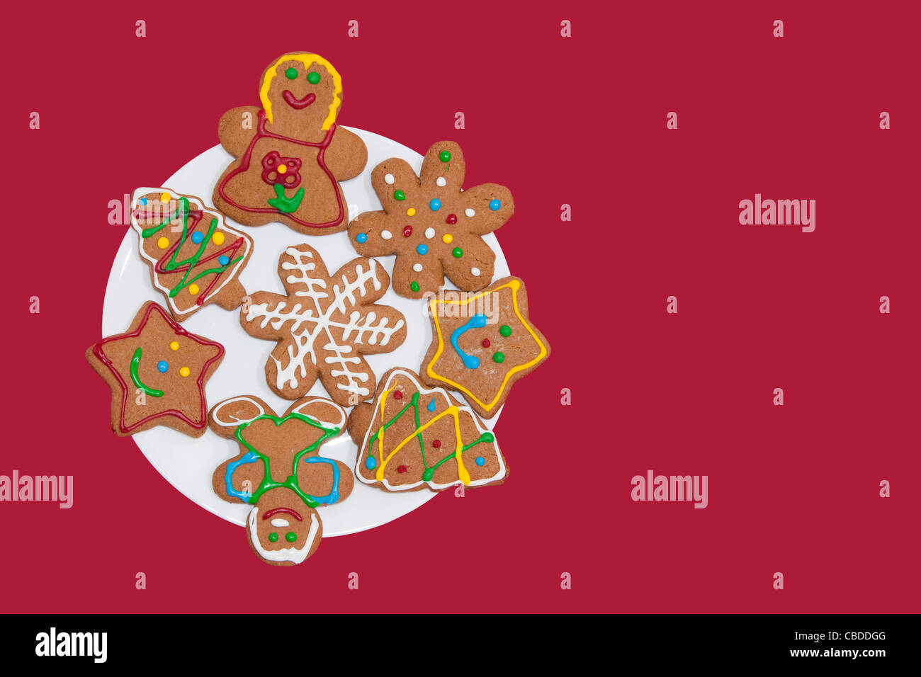 Colorful gingerbread cookies on a white plate against red background Stock Photo