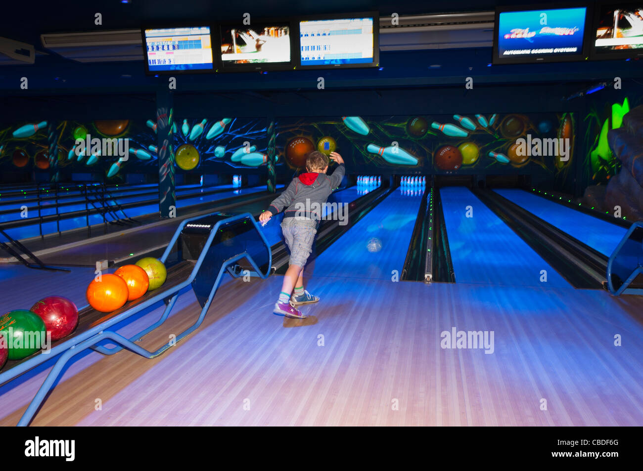 An eight year old boy ten pin bowling showing movement at Center Parcs in Elveden near Thetford , England , Britain , Uk Stock Photo