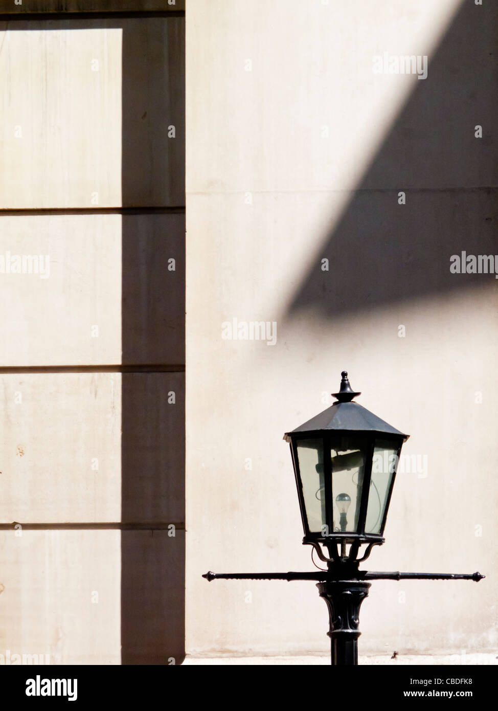 Traditional style street lamp with shadow on wall behind in the City of London UK Stock Photo