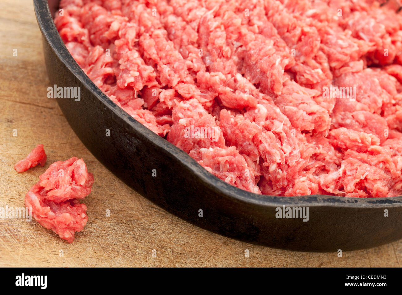 raw ground bison (buffalo) meat on an iron pan against wood surface Stock Photo