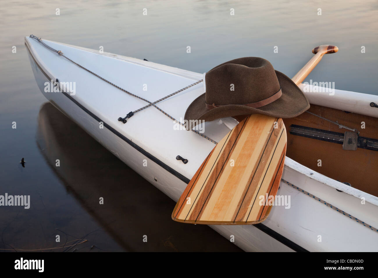 a cowboy hat,a wooden paddle across cockpit of decked expedition canoe