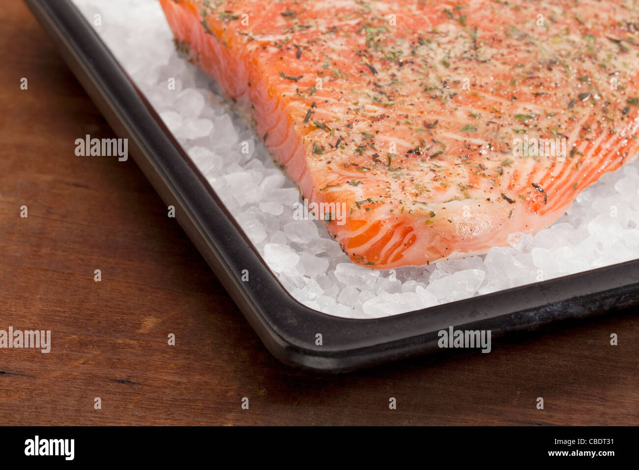 a fillet of raw Norwegian salmon, seasoned with lemon juice and thyme, ready to bake on rock salt Stock Photo