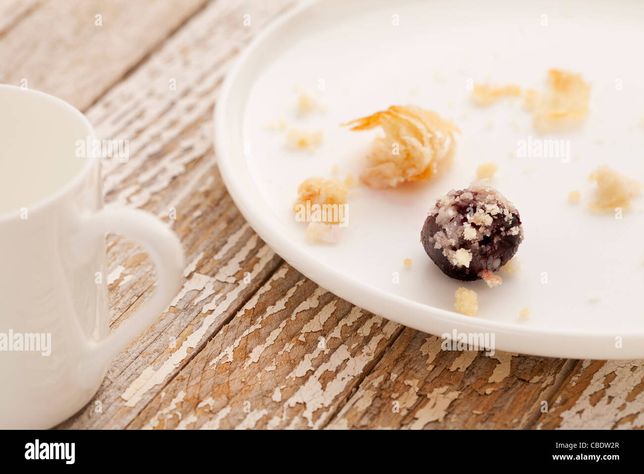 dessert gone - crumbs of cherry cheese danish pastry on white plate with espresso coffee cup on grunge wood table Stock Photo