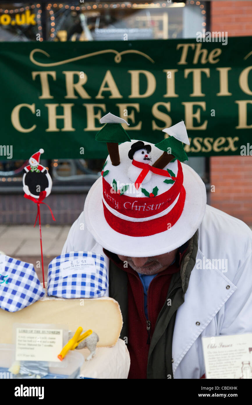 Man wearing a Christmas hat selling cheese on a market stall. Stock Photo