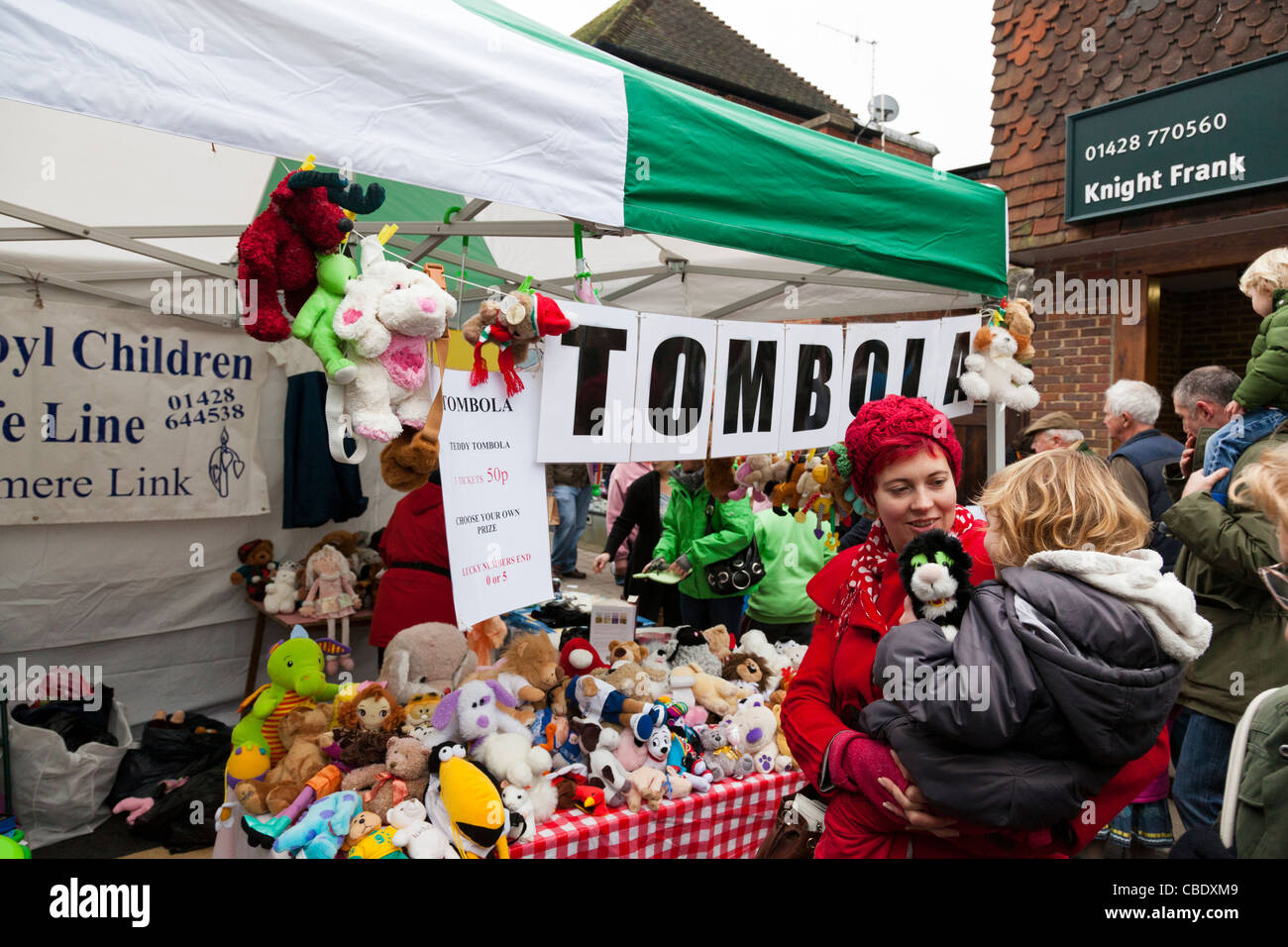 Woman with red knitted hat and child at a tombola stall at a Christmas market. Stock Photo