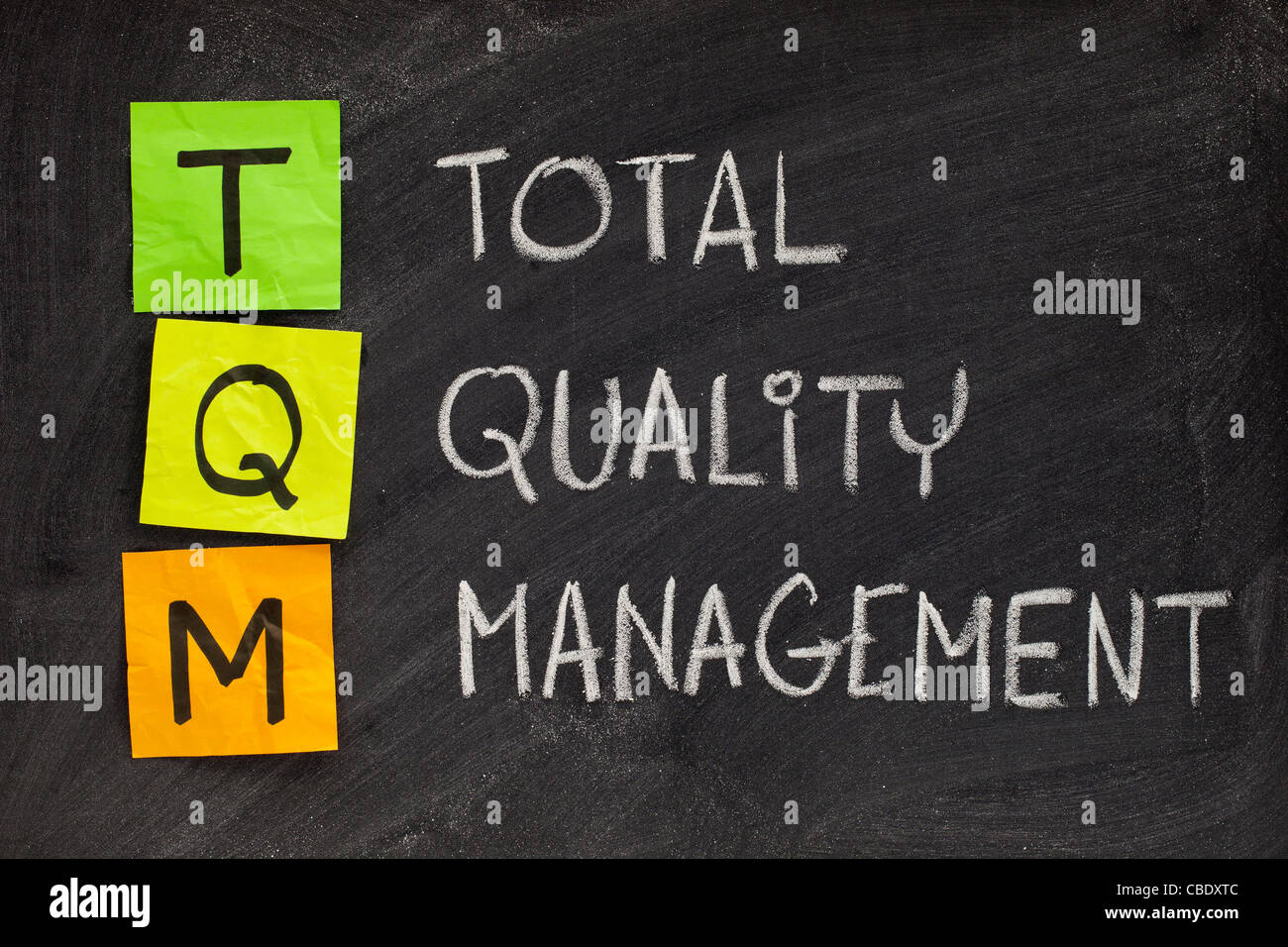 TQM acronym (total quality management) - white chalk handwriting and sticky notes on blackboard Stock Photo