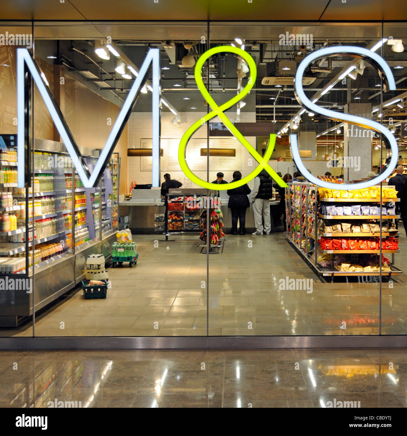 Foodhall beyond M&S illuminated store sign mounted on shop window of food hall in Westfield shopping centre Stratford City Newham East London England Stock Photo