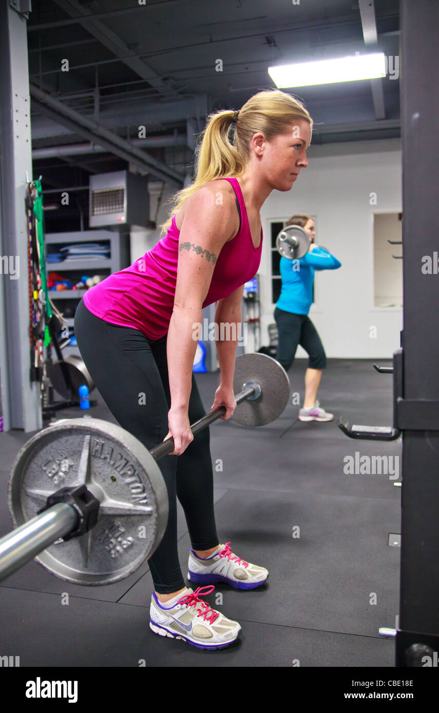 Women working out with olympic free weights in gym. Stock Photo