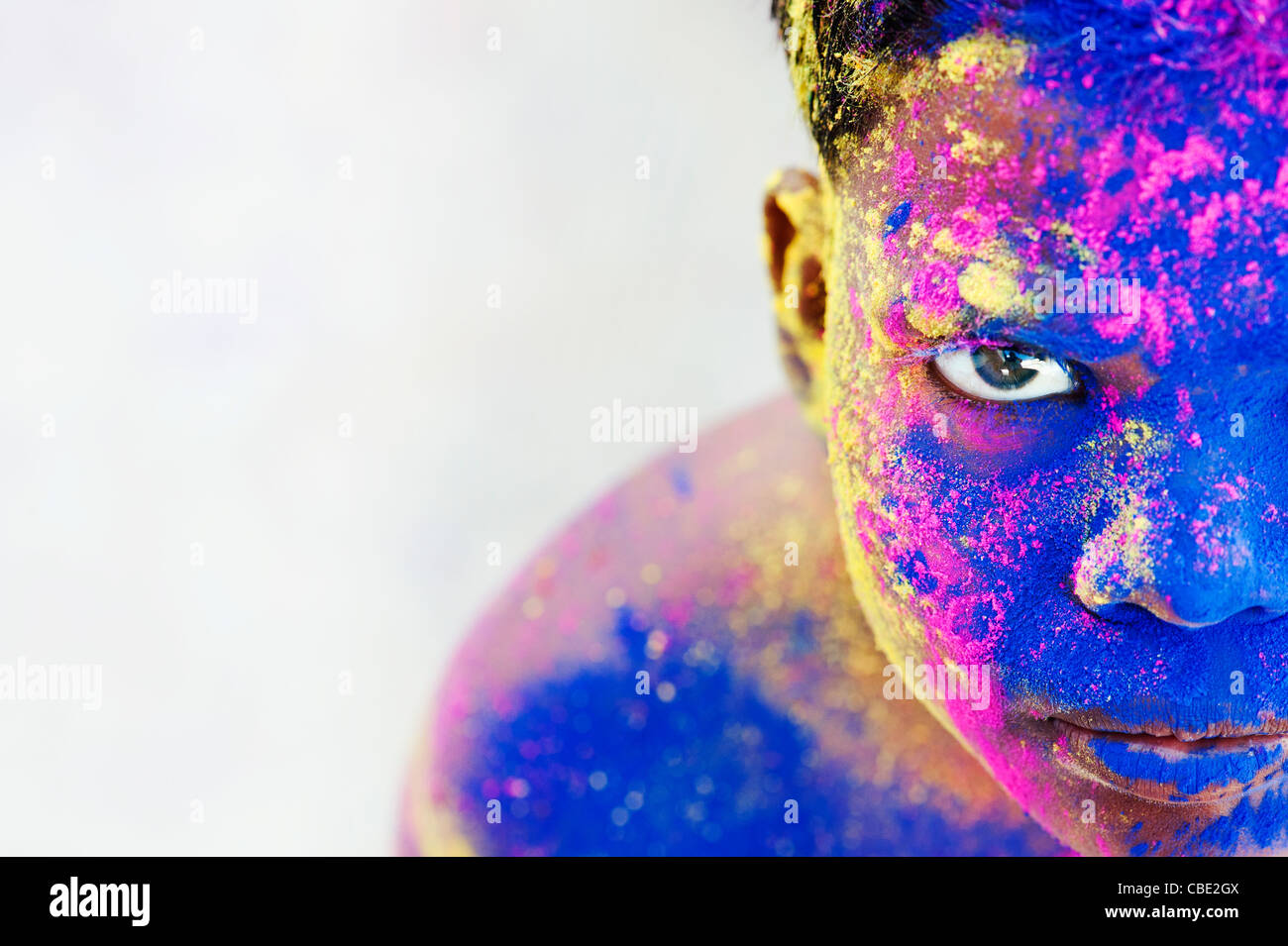 Young Indian boy covered in coloured powder pigment Stock Photo