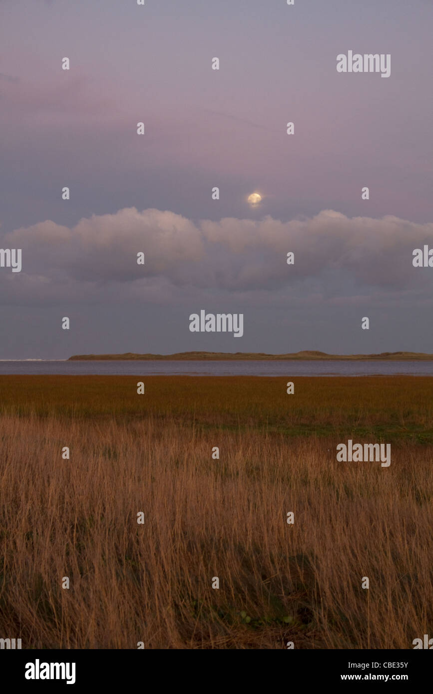 Sunset and moonrise over Lindisfarne Stock Photo - Alamy