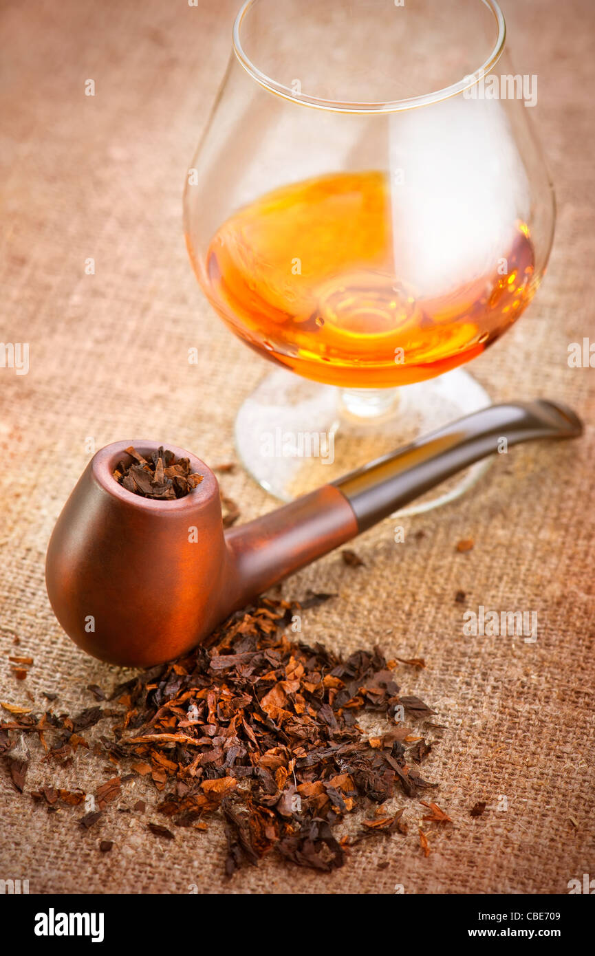 Glass of cognac and pipe with tobacco on linen canvas background Stock  Photo